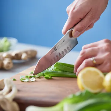 knife chopping green onions on cutting board
